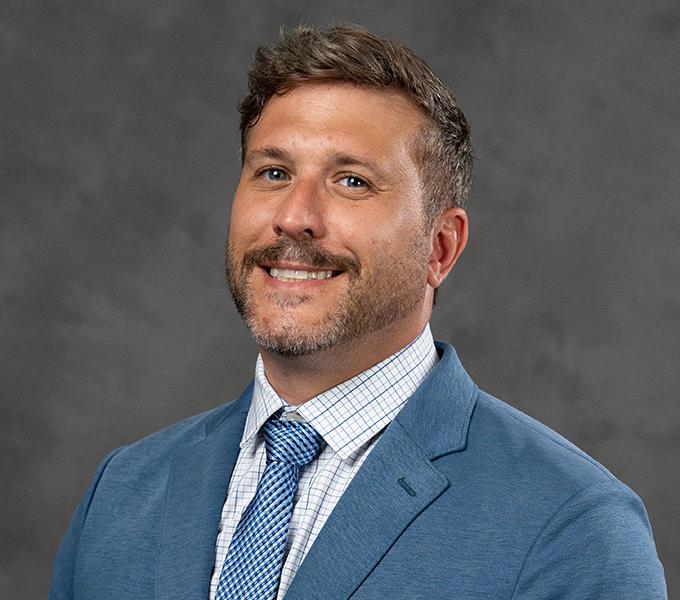 Man in blue suit with white shirt and blue tie.