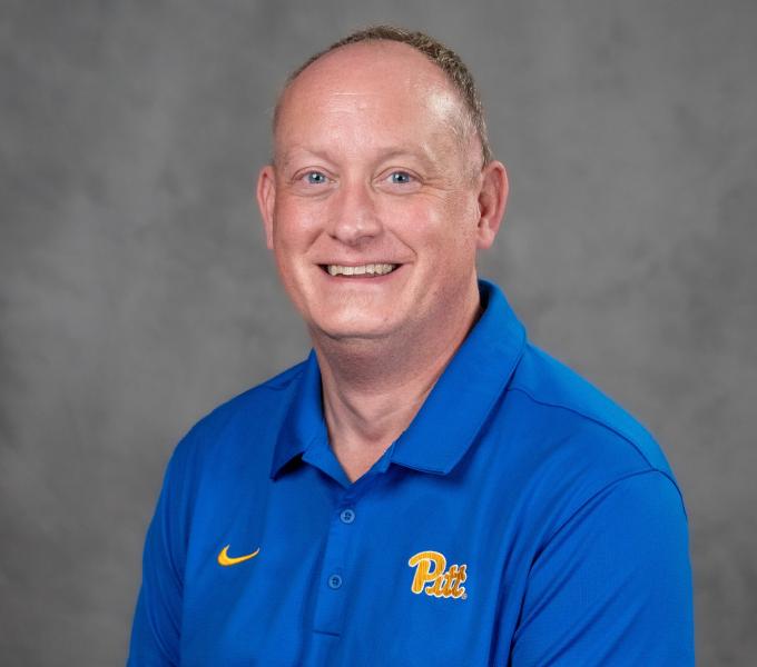 Headshot of a smiling man in a light blue Pitt polo shirt.