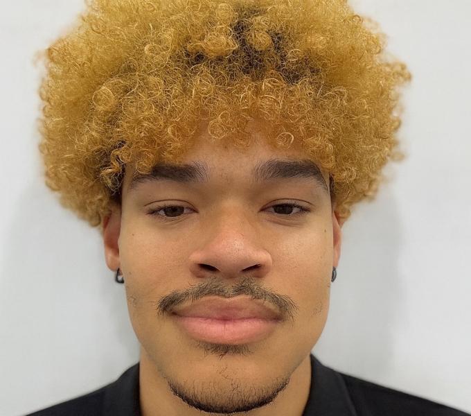 Niko Metoyer smiling in front of a white background.