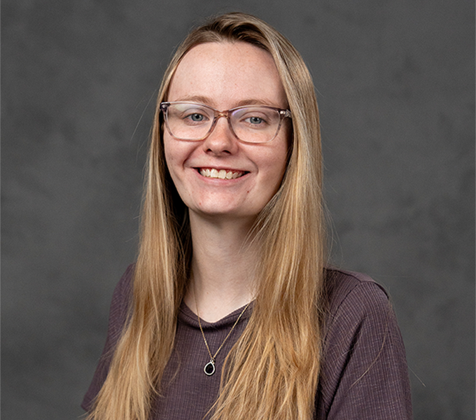 Woman in a purple shirt with glasses.