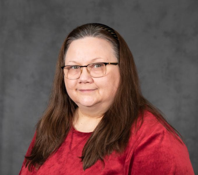 Headshot of smiling woman with brown hair in a red shirt.