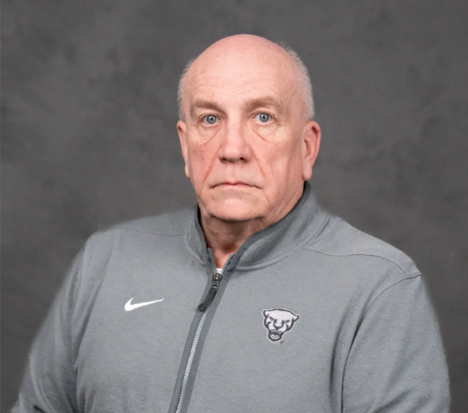 A man with white hair in a grey quarter zip sweatshirt.