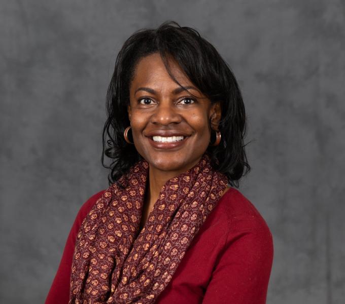 Headshot of smiling woman in a dark red shirt and scarf.