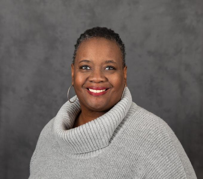 Headshot of smiling woman in an oversized light gray turtleneck sweater.