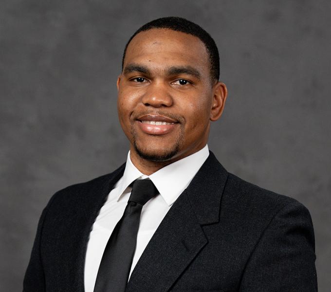 A man in a black suit smiling.