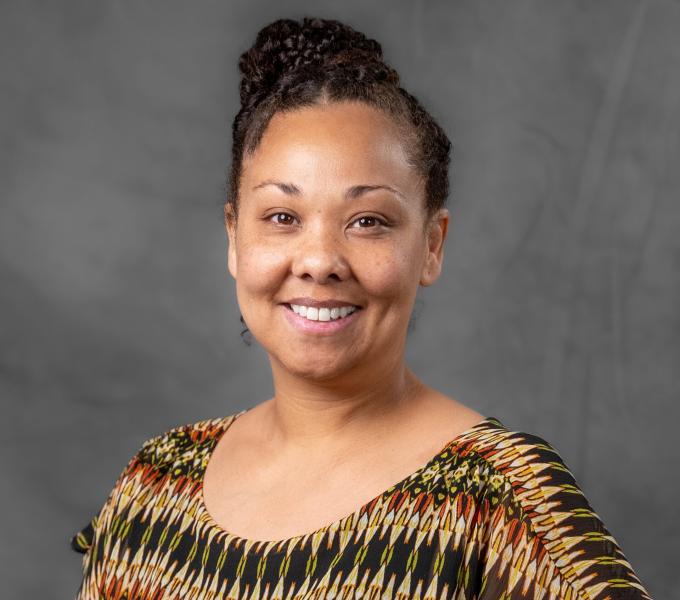 Headshot of a smiling woman in a warm patterned shirt.