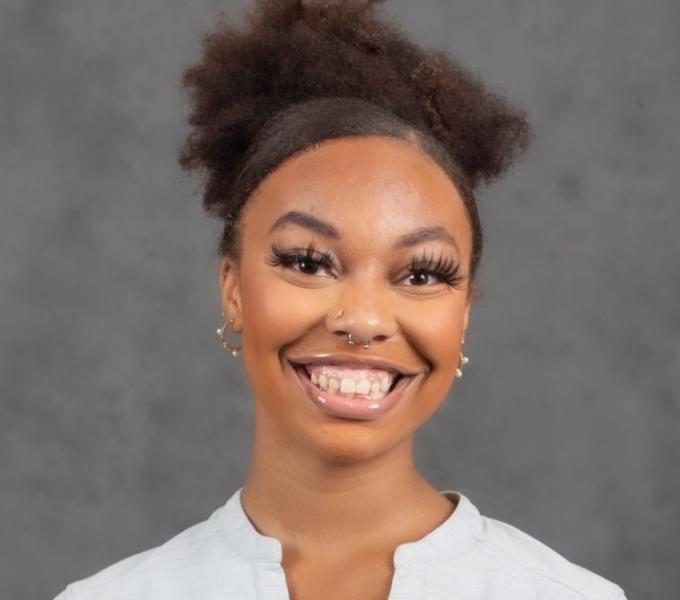 Headshot of a smiling woman in a white long-sleeved Pitt-branded shirt.