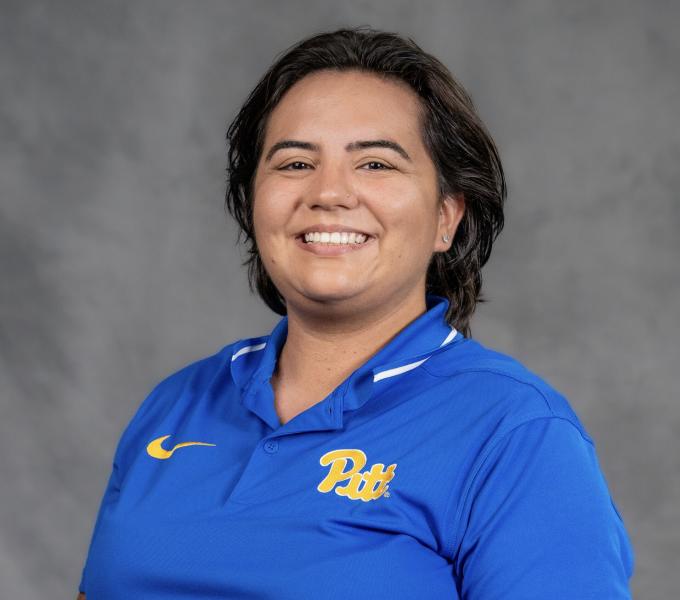 Headshot of a smiling woman with short dark hair in a blue and yellow Pitt polo shirt.