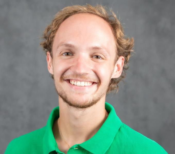 Headshot of a smiling blonde man in a bright green polo shirt.