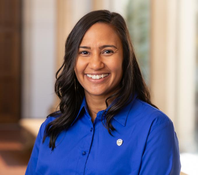 Headshot of a smiling woman with brown hair in a royal blue button-down shirt.