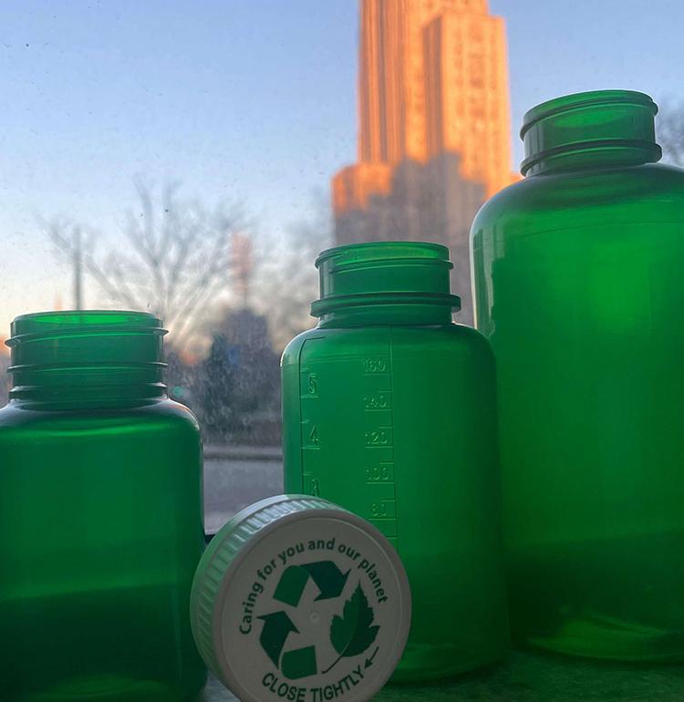 Four green plastic vials lined up along a window.